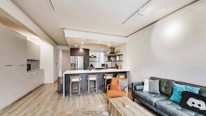 Una cucina moderna con isola centrale, sgabelli da bar e un divano con cuscini decorativi.