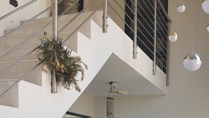 A modern interior with a staircase, metal railings, potted plants, and hanging pendant lights. - Mystic Falls Apartment on the Bay (St. Helena Bay)