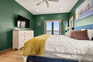 Un dormitorio con cama, cómoda, televisor y ventana con vista.