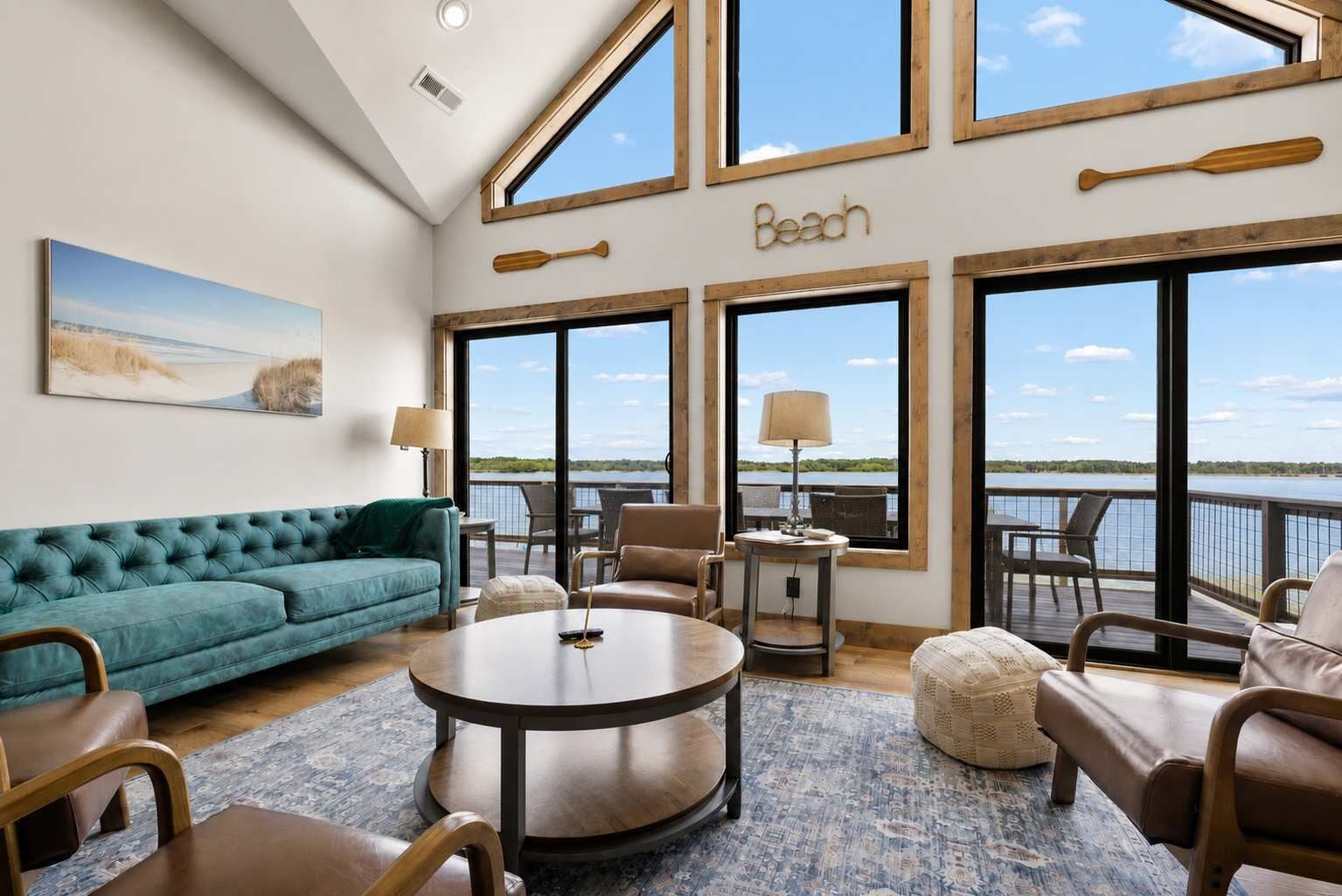 A spacious room with a large window overlooking a body of water, a comfortable seating area with a sofa and chairs, and a small table with a lamp.