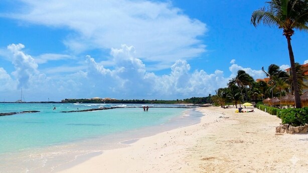 A beach with clear turquoise water, a sandy shore, and palm trees. - Caribbean getaway, private terraces, 2 minutes from the beach (Puerto Aventuras)