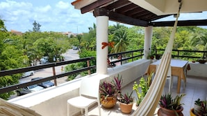 A balcony with a hammock, potted plants, a table, and chairs. - Caribbean getaway, private terraces, 2 minutes from the beach (Puerto Aventuras)