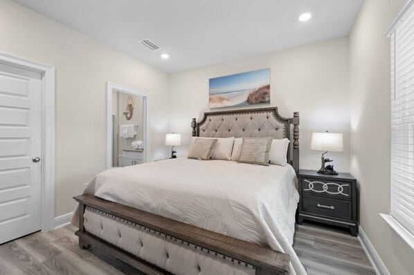 A bedroom with a large bed, two bedside tables, a door, and a picture on the wall. - Marigold House: Foley (Foley)