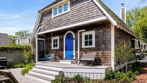 A two-story house with a blue front door, a covered porch, and a chimney. - *NEW* Historic Ptown Cottage - Dogs Welcome, Deck, Parking, Vibrant and Colorful (Provincetown)