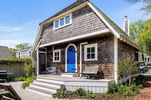 A two-story house with a blue front door, a covered porch, and a chimney. - *NEW* Historic Ptown Cottage - Dogs Welcome, Deck, Parking, Vibrant and Colorful (Provincetown)
