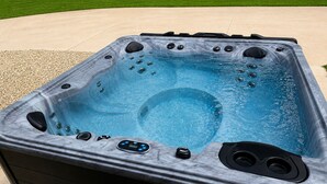 A hot tub with a control panel, built-in jets, and a clear water surface. - The Bass Shack (Alba)