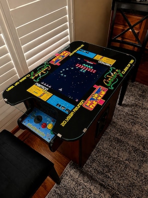 A retro arcade table with a game screen, a joystick, and a coin slot. - The Bass Shack (Alba)