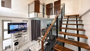 Een modern interieur met een trap, een flatscreen televisie en een plafondventilator.