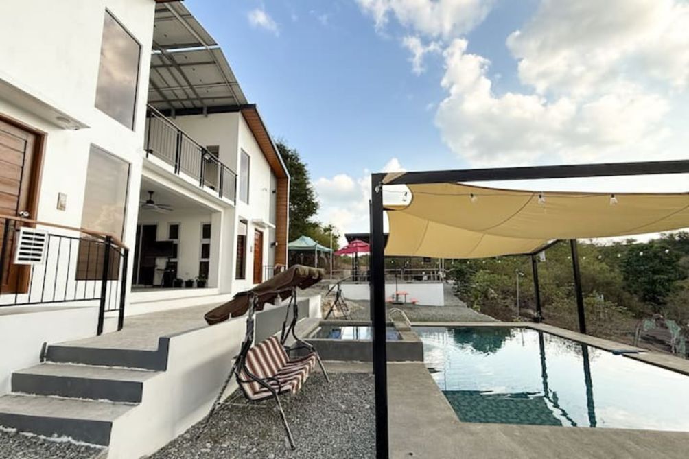 A modern house with a swimming pool, outdoor seating, and a covered patio area.