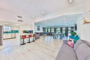 A spacious living area with a kitchen, dining area, and a large window providing natural light.