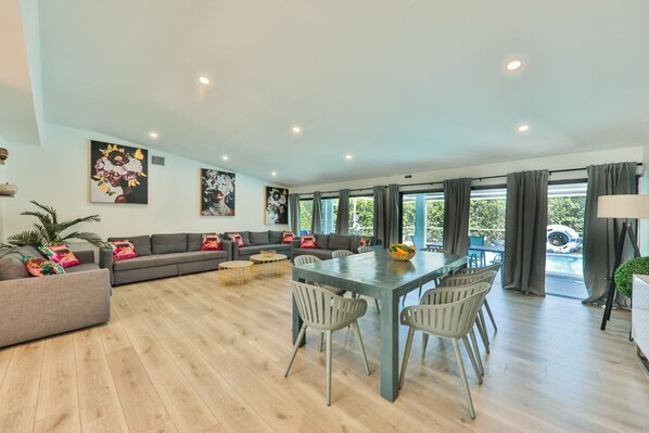 A spacious living area with a dining table, sofas, and a view of the outdoors.
