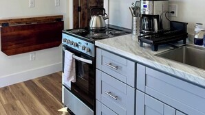 A kitchen with a built-in microwave, stove, and coffee maker. - Country Cottage - New Construction On 20 acres (Miles City)