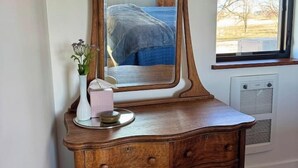 A wooden dresser with a mirror, a vase with flowers, and a tissue box. - Country Cottage - New Construction On 20 acres (Miles City)