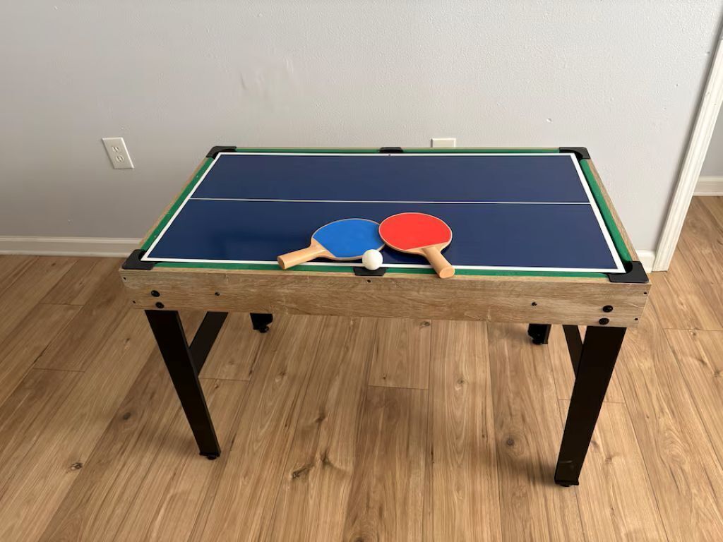 Een tafeltennistafel met twee batjes en een bal.