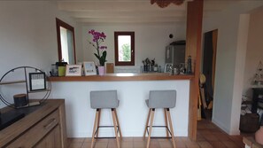 A kitchen with a wooden countertop, two grey barstools, a potted plant, and a window. - Plerin, 2-bedroom house with a large terrace and parking in the yard (Plérin)