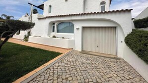 A white building with a cobblestone driveway, a garage door, and a small window. - Casa di Campara Villa Faro (Faro)