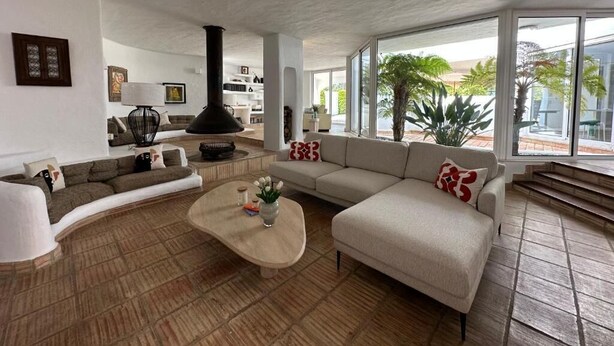 A modern living room with a curved sofa, a coffee table, and a fireplace. - Casa di Campara Villa Faro (Faro)