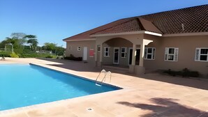 Una piscina con una scala, un edificio con tetto in tegole e un cielo azzurro limpido.