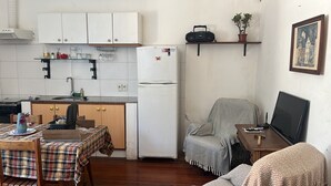 Un espace de vie compact comprenant un coin cuisine, un coin repas, un canapé et un téléviseur.