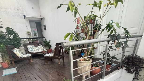 Une terrasse en bois, agrémentée de meubles d’extérieur, de plantes en pot et d’un escalier menant à un niveau supérieur.