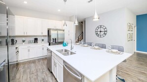 A modern kitchen with white cabinets, stainless steel appliances, and pendant lighting. - Upstay Sleeps 26 w Private Pool, Hot Tub, Games (Kissimmee)
