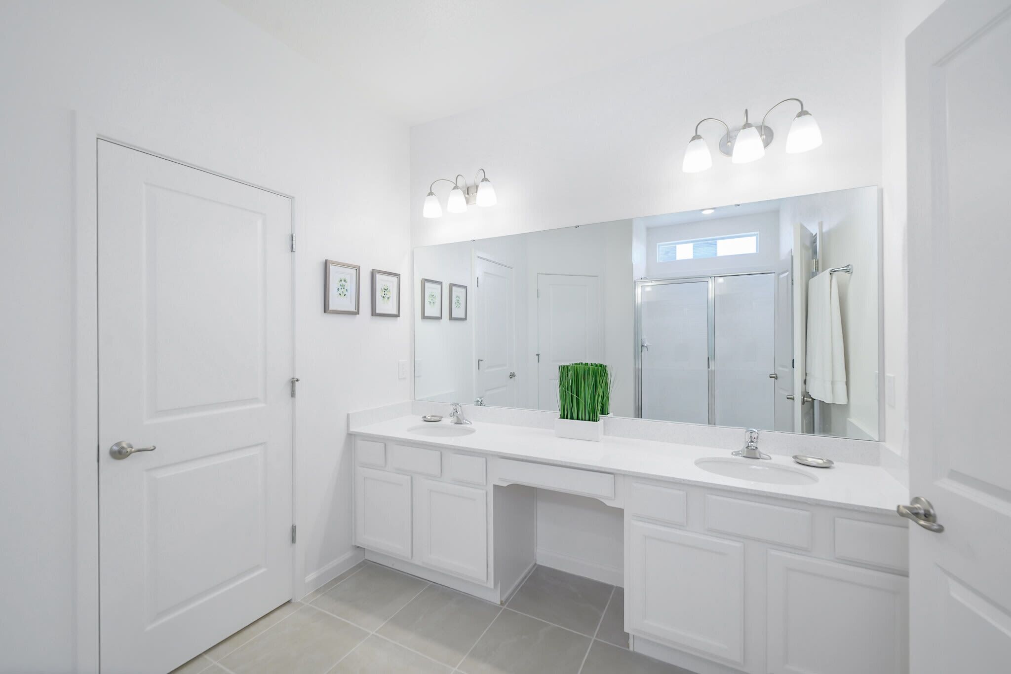 A modern bathroom with white fixtures, a large mirror, and three wall-mounted lights.