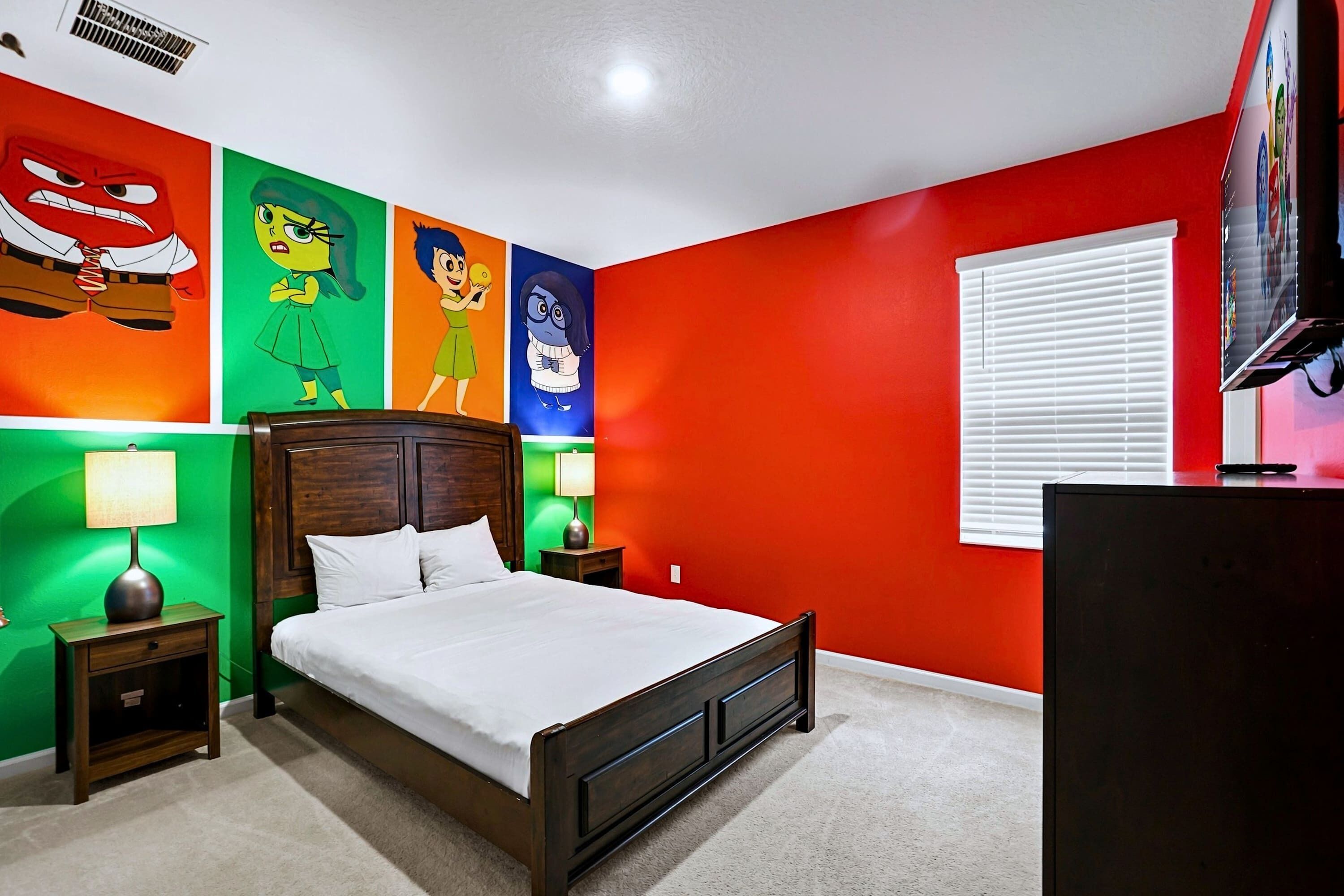 Un dormitorio con cama, mesitas de noche, televisión y decoración de pared colorida.