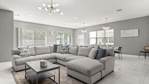 Ein modernes Wohnzimmer mit einem Ecksofa, einem Couchtisch und einem Essbereich mit Tisch für vier Personen.