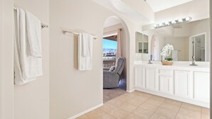 Un bagno con un ampio specchio, una toeletta e una vista attraverso un arco.