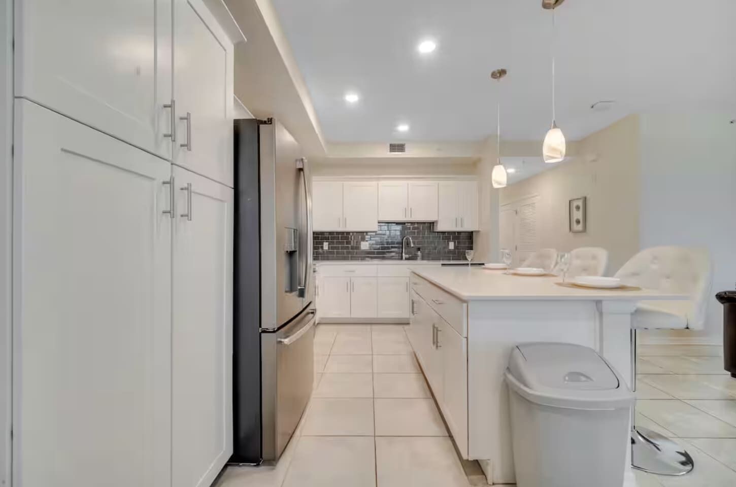 A modern kitchen with white cabinetry, a central island, and pendant lighting.