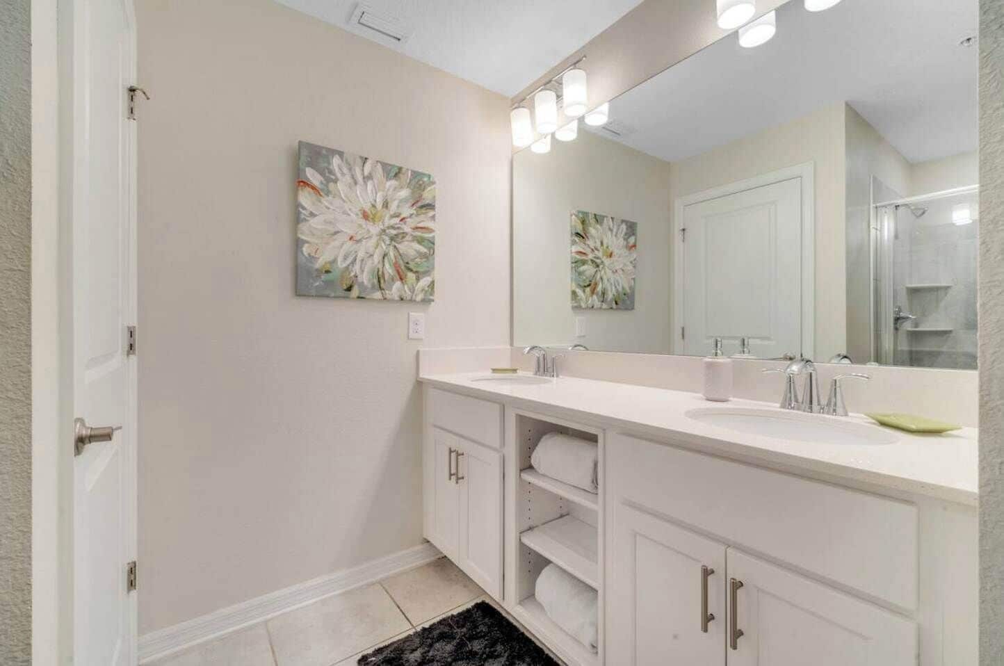 A modern bathroom with a white vanity, a large mirror, and two wall-mounted light fixtures.
