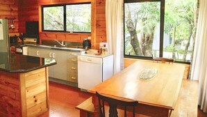 A wooden cabin interior with a kitchen, dining area, and large windows. - Puka Lodge (Front dwelling) 2 mins walk to beautiful Pukawa Bay Beach Lake Taupo (Pukawa)