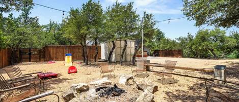Un patio al aire libre con un hogar para fuego, asientos y una valla de madera.