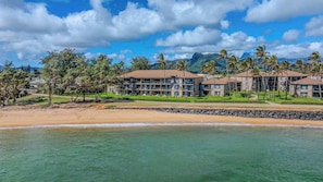 Ein Strandhotel mit mehreren Gebäuden, einem sandigen Strand und klarem türkisblauem Wasser.