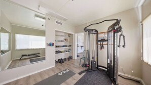 Ein Heim-Fitnessraum mit Klimmzugstange, Gewichtbank und Hanteln.