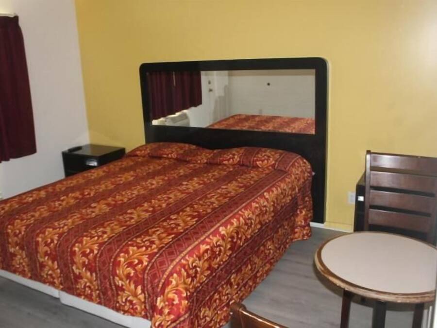 Une chambre à coucher avec un lit, une table de chevet, une chaise et un miroir.