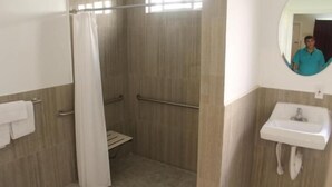 A bathroom with a shower, a toilet, a sink, and a mirror.