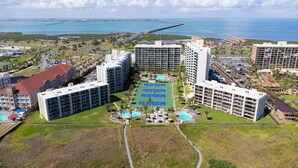 A resort with multiple high-rise buildings, a tennis court, and a swimming pool. - Wake Up to Ocean Views - Beachfront Balcony, Pool (South Padre Island)