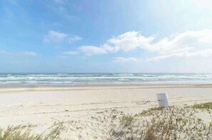 A beach with a white barrel and sparse vegetation. - Modern Beachside Condo w/ Pool-south Padre Island (South Padre Island)