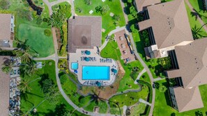 An aerial view of a resort with a central swimming pool, surrounded by pathways, palm trees, and modern buildings. - Affordable Mini Suite | Pono Kai Resort | K106 (Kapaʻa)