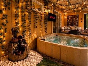 A cozy indoor setting with a hot tub, wooden walls, and a Netflix sign. - Romantic Riverfront Views Private Pool HotTub Fireplaces Pets BBQ Luxe Amenities (Jeffersonville)