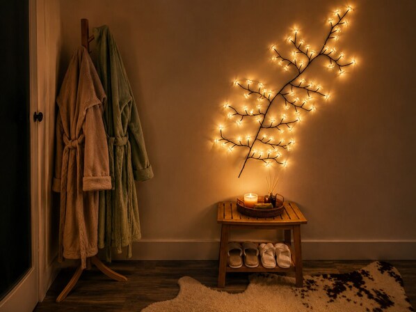 A room with a wooden floor, a white fluffy rug, a wooden side table with a candle, and a wall-mounted light fixture. - Romantic Waterfront Views BBQ HotTub Fireplaces Private Pool Pets Luxe Amenities (Jeffersonville)