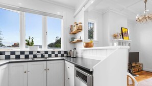 Una cocina con armarios blancos, encimera negra, lavavajillas y ventana con vistas.