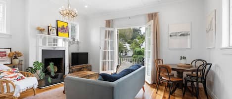 Una sala de estar con sofá, chimenea, televisor y zona de comedor con sillas y mesa.