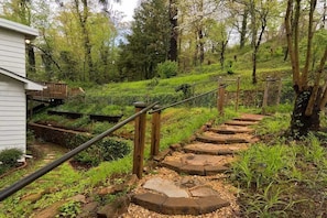 A stone staircase leading up a hill, surrounded by greenery and trees.