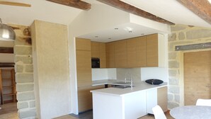 Une cuisine moderne dotée d’un îlot central, de meubles blancs et d’un mur d’accent en pierre.