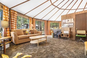 A cozy interior with a sofa, coffee table, and a desk area with a computer. - Carousel House - Retro 70's Home - SHARC (Sunriver)