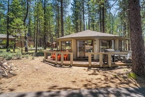 A wooden gazebo with a glass enclosure, surrounded by a deck with outdoor seating. - Carousel House - Retro 70's Home - SHARC (Sunriver)