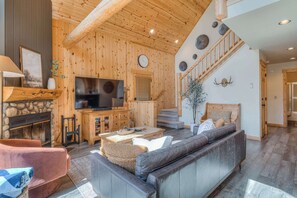 A wooden interior with a fireplace, television, sofa, and staircase. - The Nest - Golf - Hot Tub & Resort Amenities (Redmond)