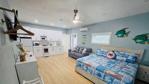 Una camera da letto con un letto, un divano, angolo cottura e una ventola a soffitto.